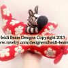 Crocheted zebra toy with black and white stripes sitting on a handmade red crochet airplane featuring white and light blue floral motifs. Amigurumi zebra and airplane crafted with detailed wings and propeller, showcasing whimsical crochet design and vibrant yarn artistry.