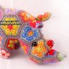 Close up of Crocheted rhinoceros soft toy made with colorful African flower motifs in hexagon and pentagon shapes; handcrafted using bright yarns in pink, red, orange, yellow, blue, and purple, forming a detailed 3D animal figure—pattern by Heidi Bears Designs.