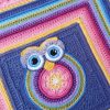 Owlie 2.0 crochet kit A colourful crocheted owl square with a central owl motif in pink, purple, yellow, and blue, set against a dark blue background and bordered with bright yellow, pink, purple, and blue rounds.