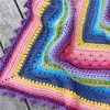 Owlie 2.0 crochet kit Multicoloured crocheted blanket with textured stitch patterns arranged in concentric squares.