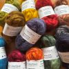 ColourSpun Kid Mohair Roving in a rich collection of hand dyed colours including olive, gold, purple, red, orange, teal, pink, brown and grey, displayed on a wooden surface.