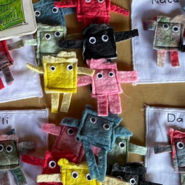 A colourful pile of handmade felt monster characters with googly eyes, in shades of pink, yellow, blue, red, green and black.