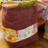 Close up of a handmade brown project bag with a hand embroidered floral fabric band and a soft green drawstring lining.