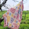 The Namaqua Blanket draped over the bare branches of a tree with a green field behind