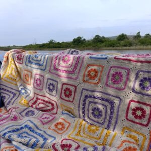 The Namaqua Blanket draped over the side of a boat with calm water and reeds behind