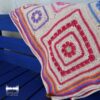 A close view of the Namaqua Blanket's diamond motifs in magenta, purple and blue, draped over the arm of a blue painted wooden bench