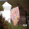 The Namaqua Blanket hanging over a black wrought iron gate beside a white pillar, with open veld and hills behind