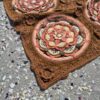Close up of the Over the Coral Sea crochet blanket by Hooked on Sunshine, made in ColourSpun Pure Cotton DK. A round mandala motif in coral, blush pink, butter yellow, cream and sage green sits in a textured caramel brown border with a raised crochet rose, on sand scattered with small shells.