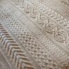 Close up of the Aran Caresse Cable Afghan by Hilda Steyn showing a twisted cable panel beside lattice and braided panels in cream