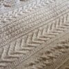 Detail of the Aran Caresse Cable Afghan showing a chevron panel and a braided cable panel in natural cream yarn