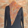 Long point of a hand dyed multicoloured shawl hanging down the front of a black mannequin, showing the striped garter stitch and a scalloped edge